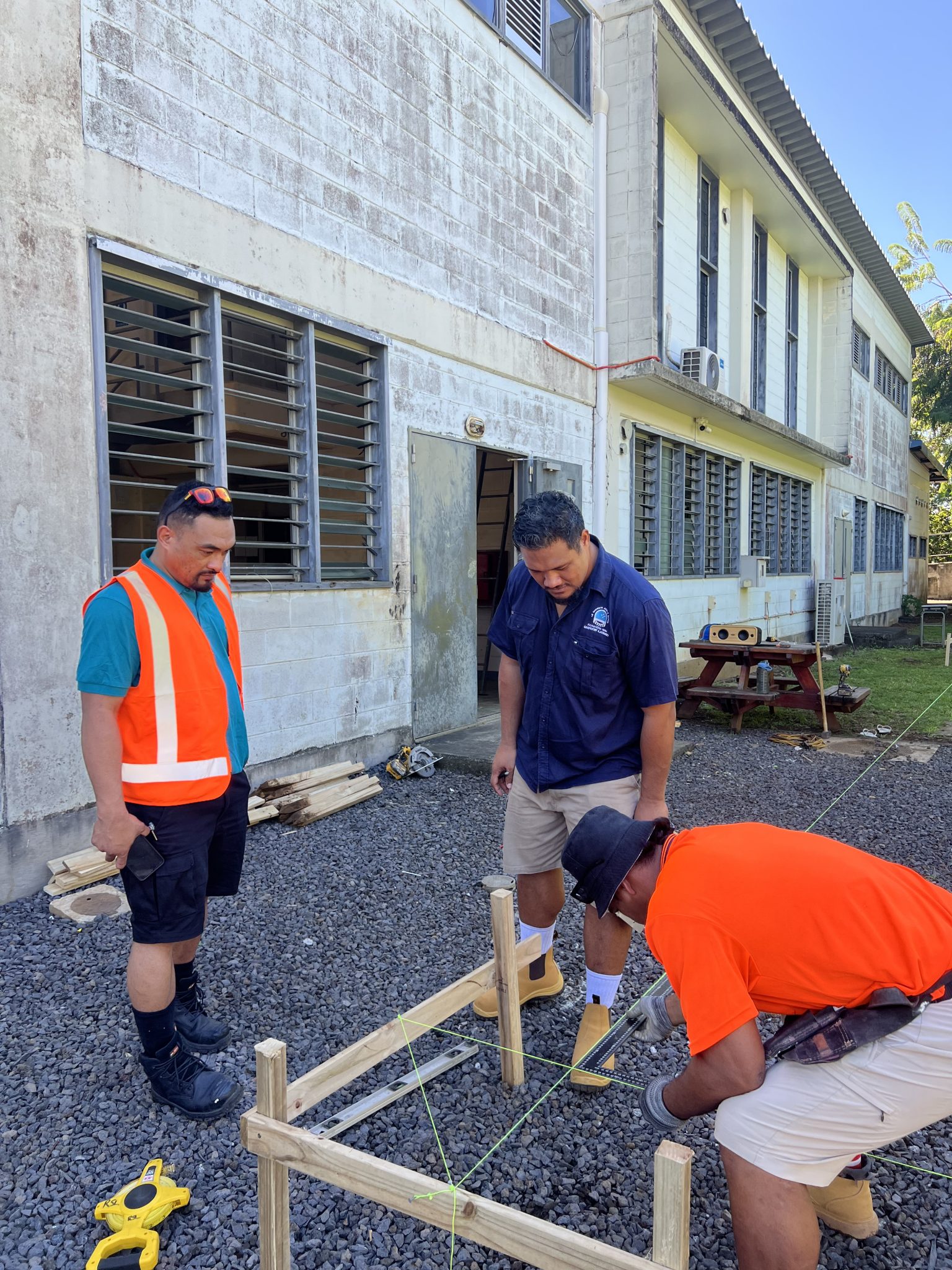 Participants measuring and setting out a timber frame on the grounds outside the workshop.