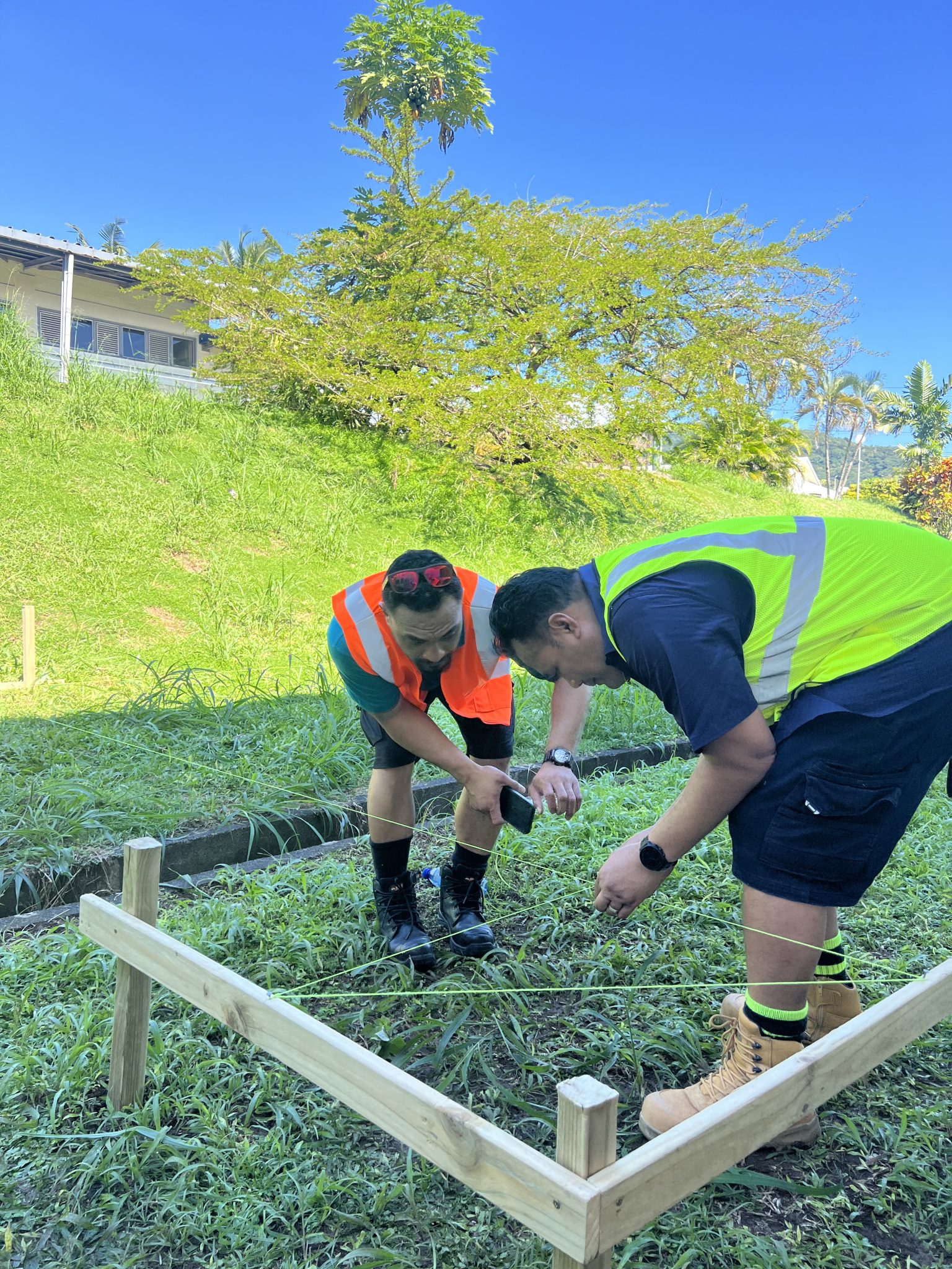 Two participants checking the layout of a timber frame on the lawn.