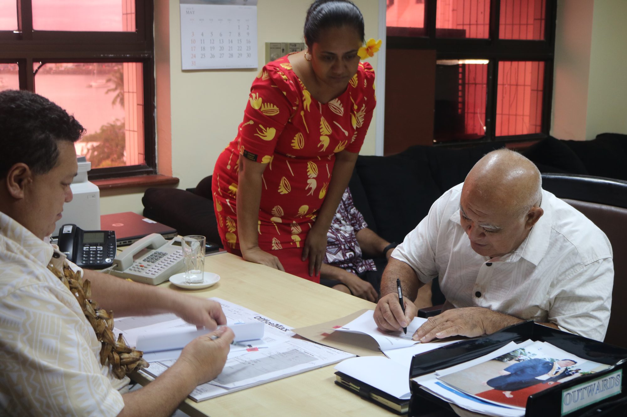 A newly appointed Commissioner signing his contract, assisted by a ministry officer.