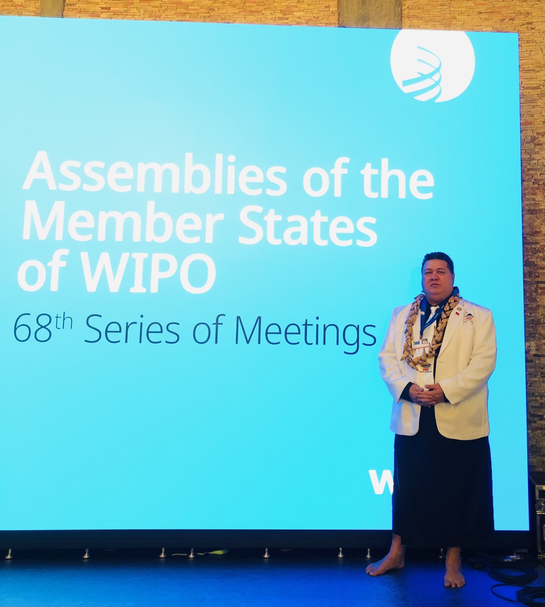 The Honourable Fata Ryan Schuster stands before the WIPO 68th Series of Meetings backdrop in Geneva.