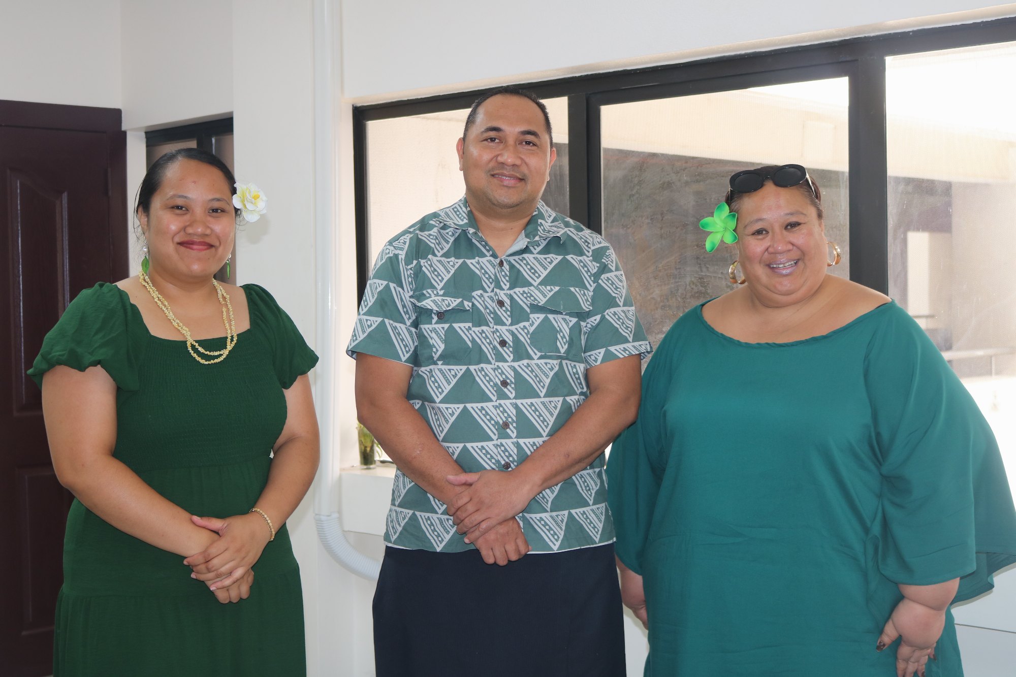 Three MCIL staff in green attire pose together in the office